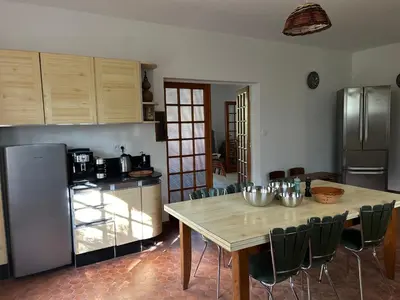 a kitchen with a table with chairs and a refrigerator at Gîte les Mercieres la Villa Maison campagne grands espaces oasis de nature, convivialité, détente 5 Chambres piscine chauffée Wifi piano billard in Pexiora