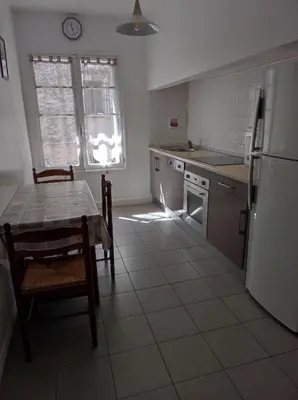 a kitchen with a table and chairs and a refrigerator at Maison vigneronne in Ribaute