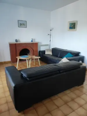 a living room with a black couch and a table at Maison vigneronne in Ribaute