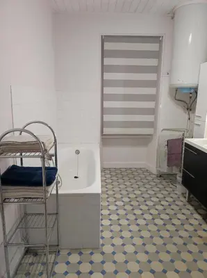 a bathroom with a tub and a tile floor at Maison vigneronne in Ribaute