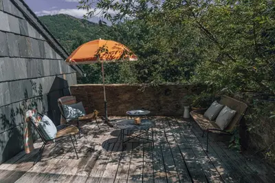 a patio with a table and chairs and an umbrella at Fount Estremiero Apartment wellness and pool shared with B&B in Castans