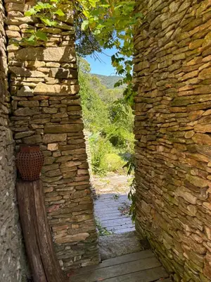an opening in a stone wall with a wooden walkway at Fount Estremiero Apartment wellness and pool shared with B&B in Castans