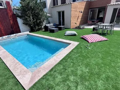 a backyard with a swimming pool and green grass at Maison climatisée, piscine, à 5 minutes des Grands Buffets in Narbonne