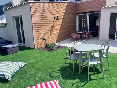 a patio with a table and chairs on the grass at Maison climatisée, piscine, à 5 minutes des Grands Buffets in Narbonne