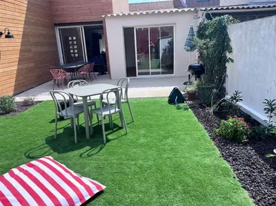 a patio with a table and chairs on the grass at Maison climatisée, piscine, à 5 minutes des Grands Buffets in Narbonne