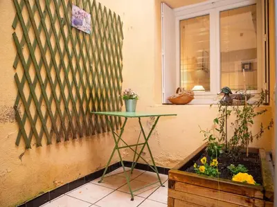 a small green table next to a window with a plant at Oustal de Papé le calme au cœur de Mirepoix in Mirepoix