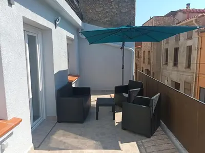 a patio with chairs and an umbrella on a balcony at Appartement calme in Salses-le-Chateau