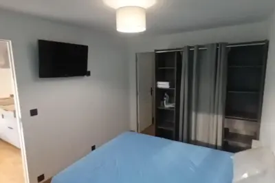 a bedroom with a blue bed and a tv at Appartement calme in Salses-le-Chateau