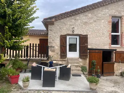 a house with a table and chairs in front of it at Gîte Appartement à la campagne in Lautrec
