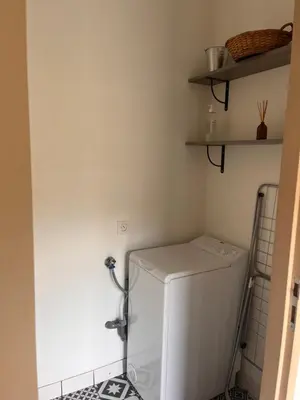 a laundry room with a white refrigerator and shelves at Gîte Appartement à la campagne in Lautrec