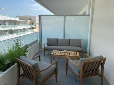 a balcony with a couch and two chairs and a table at Très beau F2 neuf 50 M2 , grande terrasse 30 M2, très bien situé in Narbonne