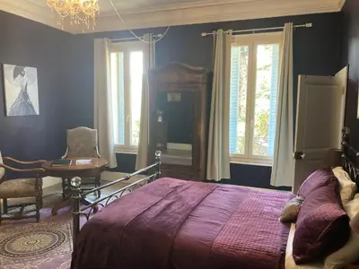 a bedroom with a bed and a desk and windows at La Villa Celine in Saint-Laurent-de-la-Cabrerisse