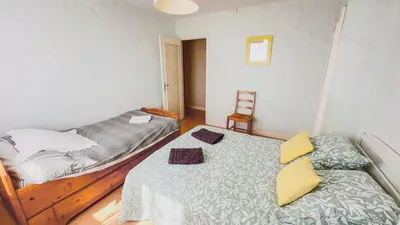 a bedroom with two beds and a chair at Gîte Familial du Vintrou in Le Vintrou