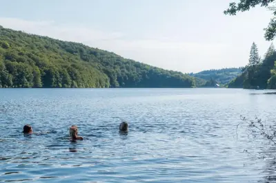 two people are swimming in a large lake at Gîte Familial du Vintrou in Le Vintrou