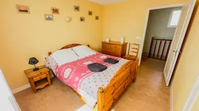 a bedroom with a wooden bed with a red and white comforter at Gîte Familial du Vintrou in Le Vintrou