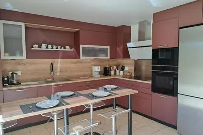 a kitchen with red cabinets and a table with stools at Ostau Agradiu - Maison de maître proche de la Mer in Peyriac-de-Mer