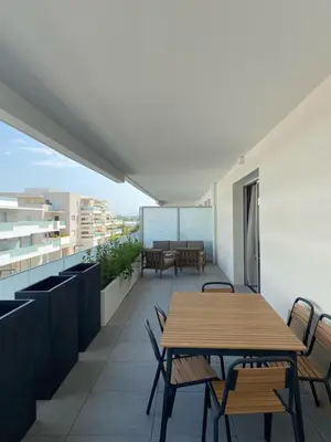 a balcony with a wooden table and chairs at TRES BEL F2 NEUF, GRANDE TERRASSE, TRES BIEn SITUE in Narbonne