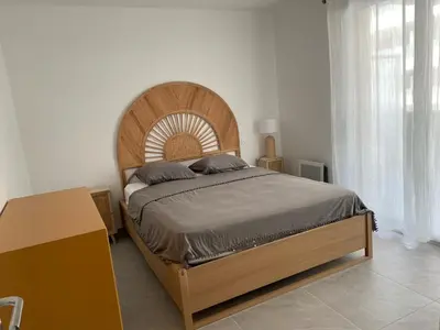 a bedroom with a large bed with a wooden headboard at TRES BEL F2 NEUF, GRANDE TERRASSE, TRES BIEn SITUE in Narbonne