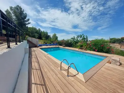 a swimming pool on a wooden deck next to a building at Villa au calme, tout confort clim piscine wifi 7 personnes in Caunes-Minervois