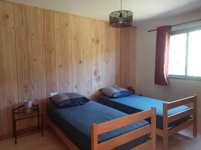 two beds in a room with wooden walls at Ecogîtes Camparols in Prémian