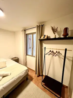 a bedroom with a bed and a shelf with hangers at Chambre de la bastide 102 in Carcassone