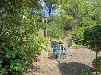 two chairs sitting around a table in a garden at Ma Zénitude in Palaja