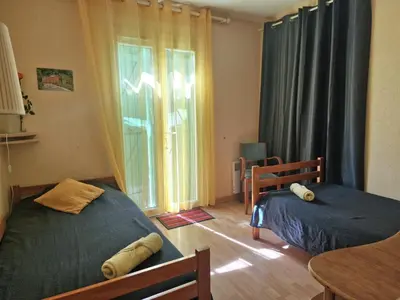 a bedroom with two beds and a table and a window at Ma Zénitude in Palaja