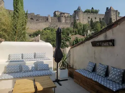 a balcony with blue and white pillows and a castle at Le Belvédère St Gimer in Carcassonne
