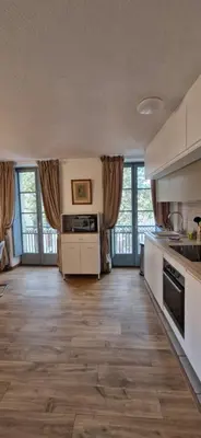 a kitchen with white cabinets and wooden floors and windows at Via Narbona in Narbonne