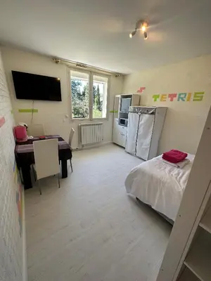 a room with a bed and a table and a kitchen at Chambre Familiale Tetris in Castres