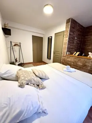 a large white bed in a room with a brick wall at Les chambres de la bastide - 103 in Carcassonne