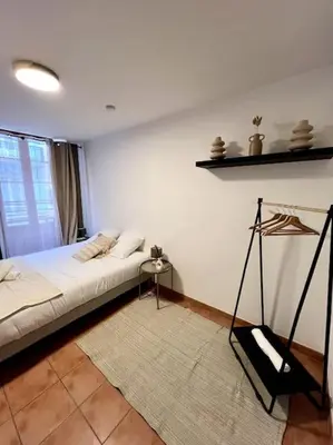 a bedroom with a bed and a white wall at Les chambres de la bastide - 103 in Carcassonne