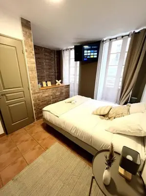 a bedroom with a bed and a table and a window at Les chambres de la bastide - 103 in Carcassonne