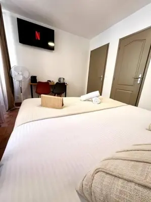 a bedroom with two beds and a tv on the wall at Les chambres de la bastide - 105 in Carcassone