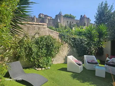 a garden with chairs and a castle in the background at Le Clos Barbacane in Carcassone