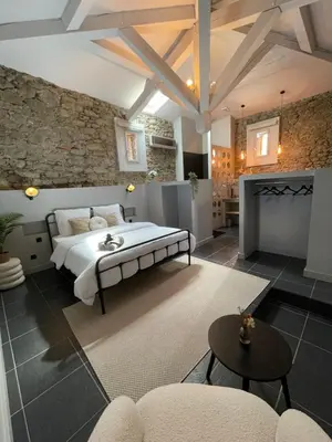 a bedroom with a large bed and a stone wall at La Tuilerie du Bazalac in Trèbes