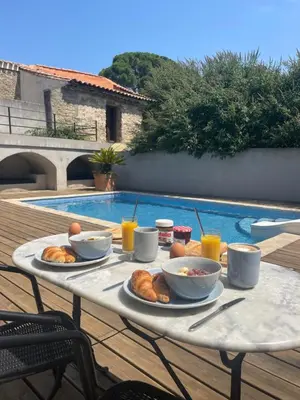 a table with food and drinks on it next to a pool at La Tuilerie du Bazalac in Trèbes