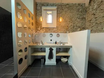 a bathroom with two sinks and a stone wall at La Tuilerie du Bazalac in Trèbes