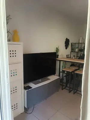 a living room with a tv on a white cabinet at Charmant T2 proche centre ville in Narbonne