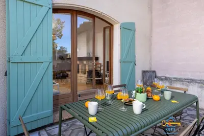 a green table with wine glasses and oranges on it at Maison Jade - Villa avec piscine - Barbecue - Calme in Narbonne