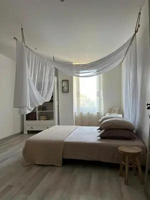 a white bedroom with a large bed with a window at La Pause Bonheur - La Vagabonde in Luc-sur-Orbieu