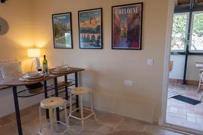 a dining room with a table and some pictures on the wall at Les Deux Petits Pois in Fanjeaux