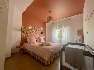 a bedroom with a bed with pink pillows on it at T2 refait à neuf Calme et agréable in Narbonne