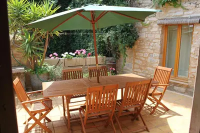 a wooden table and chairs with a green umbrella at Gite les Volets Verts in Cesseras