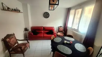 a living room with a table and a red couch at Appartement central avec parking in Carcassone
