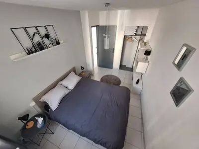 a small bedroom with a blue bed and a bathroom at Appartement central avec parking in Carcassone