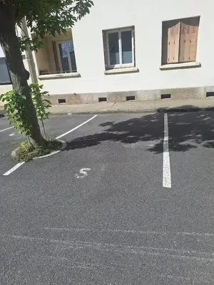 an empty parking lot with a tree and a building at Appartement central avec parking in Carcassone