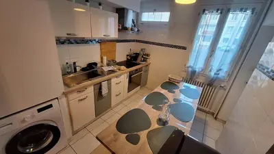 a kitchen with a table and a washing machine at Appartement central avec parking in Carcassone