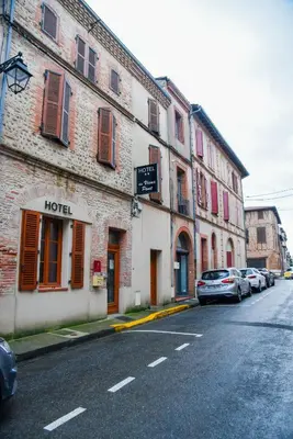 a street with cars parked on the side of a building at Hôtel du vieux pont in Mazères