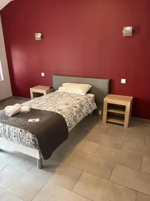 a small bedroom with a bed and two tables at Hôtel du vieux pont in Mazères
